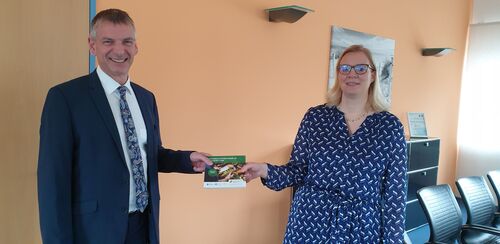 Die Leiterin der Stabsstelle Kreisentwicklung Yvonne Grein überreicht Landrat Frank Kilian die erste Broschüre des neuen Einkaufsführers.