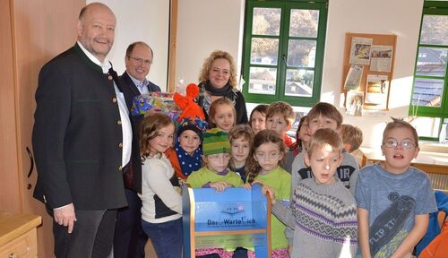 Das „Warterich“ wird von Landrat Burkhard Albers an Bürgermeister Udo Scheliga im Beisein von Sabine Stemmler überreicht. Die Kinder freuen sich auf die mitgebrachten Bücher.