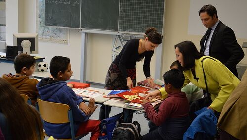 Jacqueline Brand vom Staatlichen Schulamt und Bürgermeister Reimann schauen den Schülern beim Erlernen der deutschen Sprache über die Schulter.