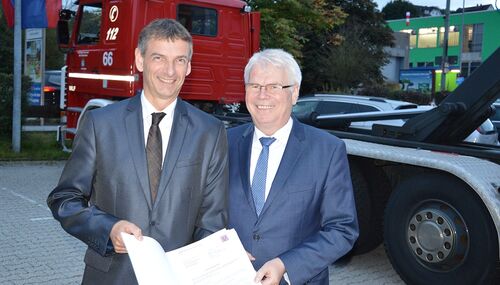 Staatssekretär Werner Koch überreicht Landrat Kilian die Bewilligungsbescheide für die beiden Wechsellader Fahrzeuge mit Containern.