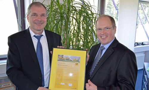 Landrat Albers nimmt das Zertifikat aus den Händen von Lothar Schindler von der Deutschen Post AG entgegen.