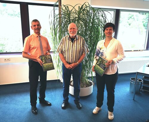 Dr. Wolfgang Ehmke überreicht Landrat Frank Kilian und der Leiterin des Fachdienstes Umwelt, Antje Schulz, zwei Exemplare des Buches „Taunusflora“.