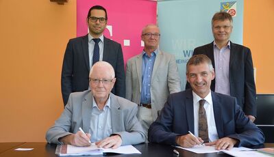 Landrat Frank Kilian und sein Stellvertreter Dr. Herbert Koch unterzeichnen schon einmal im Beisein von Fuat Dalar (Telekom), Achim Staab und Thomas Jüngling (Telekom) den Vertrag